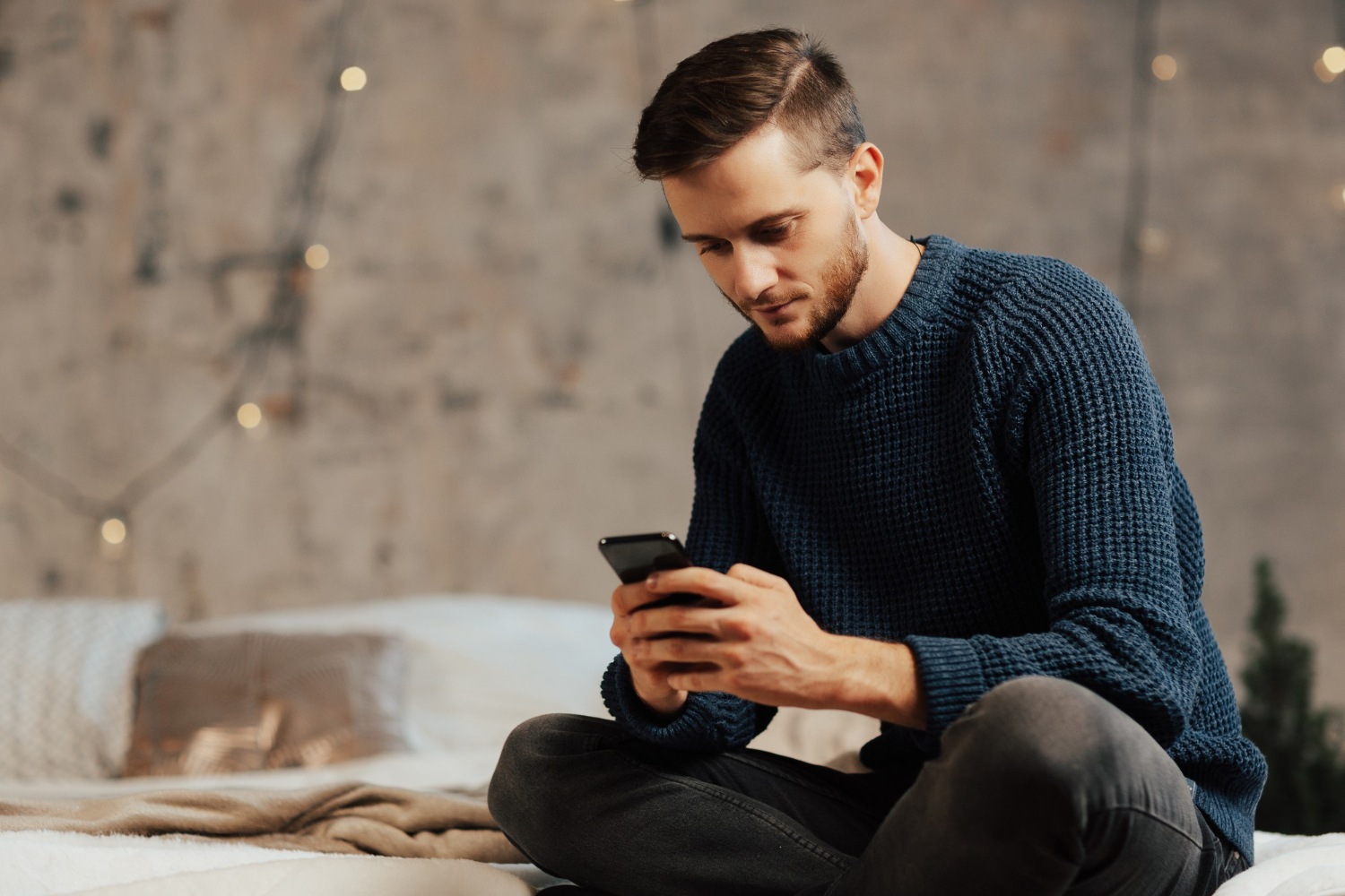 a man sits on a sofa with a phone in his hands